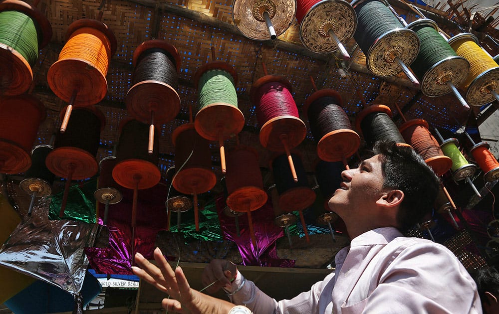 An Indian vendor winds strings for kites as he waits for customers at his shop ahead of the Hindu festival of Makar Sakranti, also knowns as kite festival, in Hyderabad.