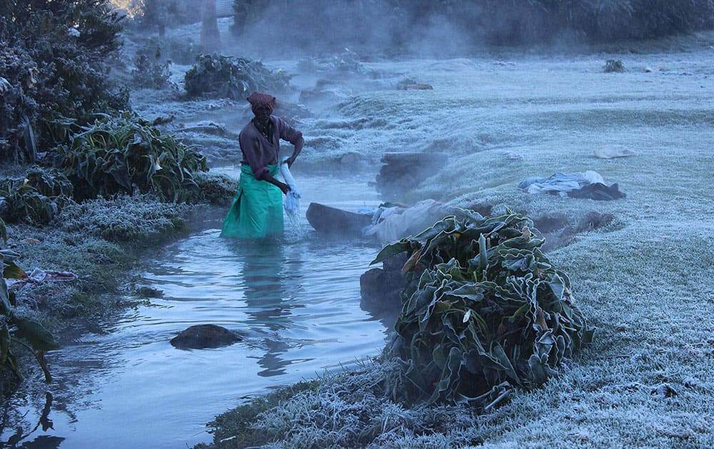 A washerman washes clothes in the chilling stream of water as the temperature dips in the hill station of Ooty located in the Nilgiri Hill.