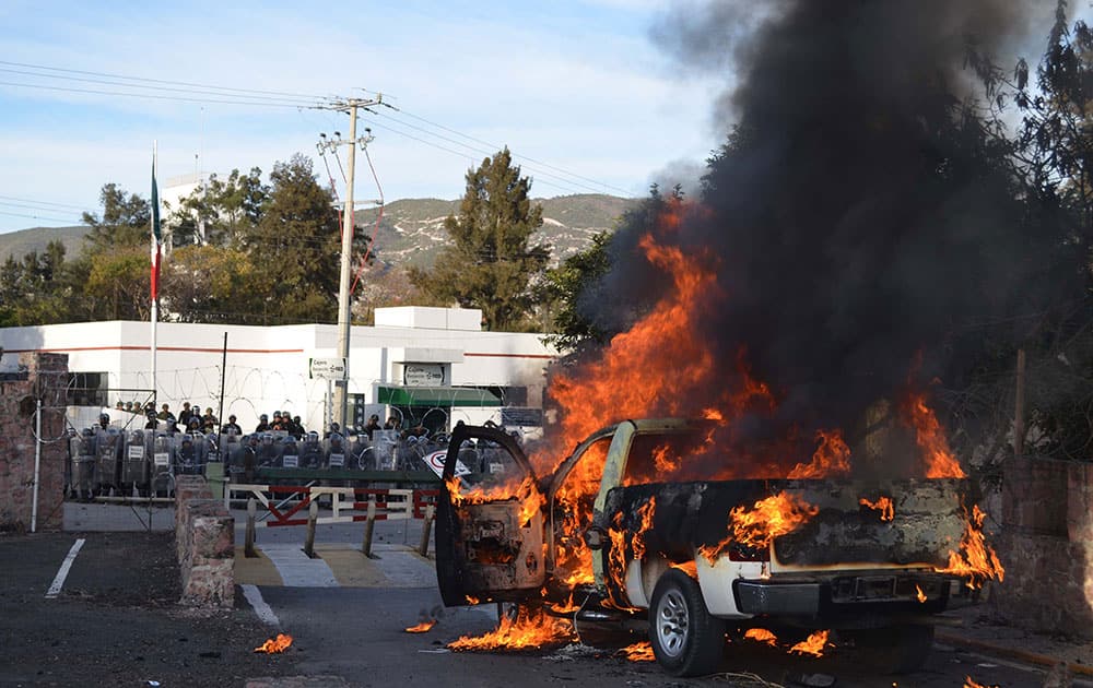 A pick-up truck burns in front of an army base after protesters set it on fire in the city of Chilpancingo, Mexico.