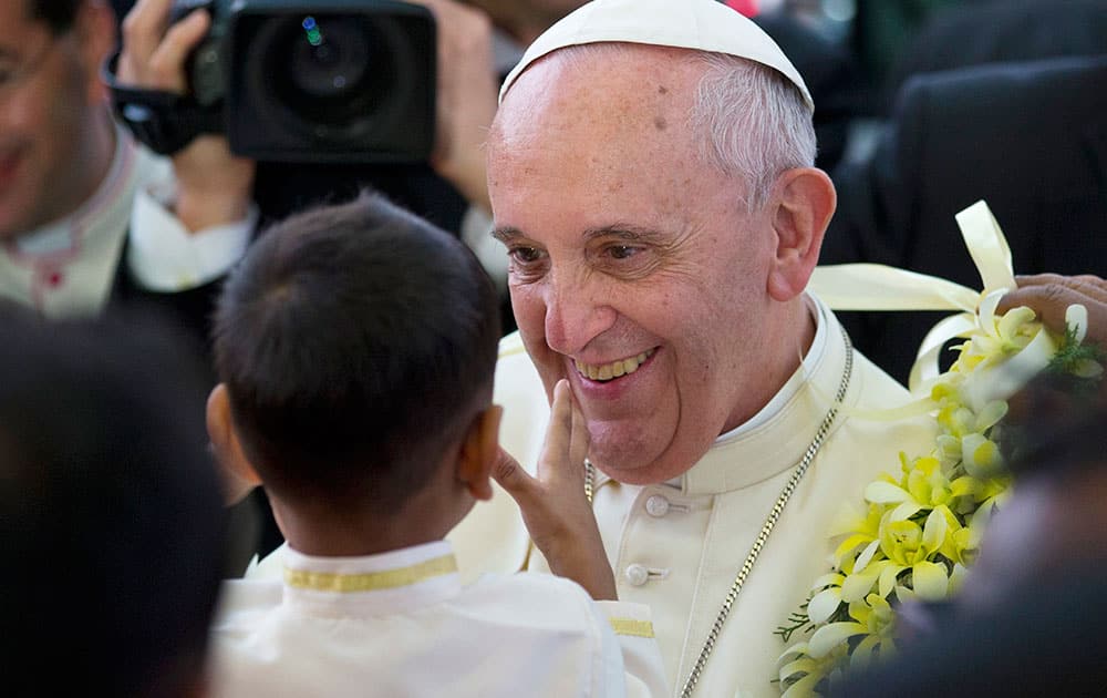 Pope Francis smiles after getting a garland from a child as he arrives for an interfaith meeting in Colombo, Sri Lanka.