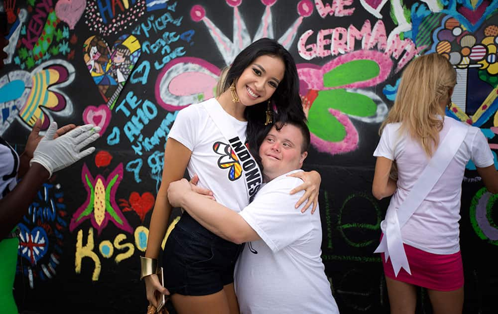 Miss Indonesia, Elvira Devinamirea, left, poses for photos with Chris Gay after she painted on a wall in Miami's Wynwood area.