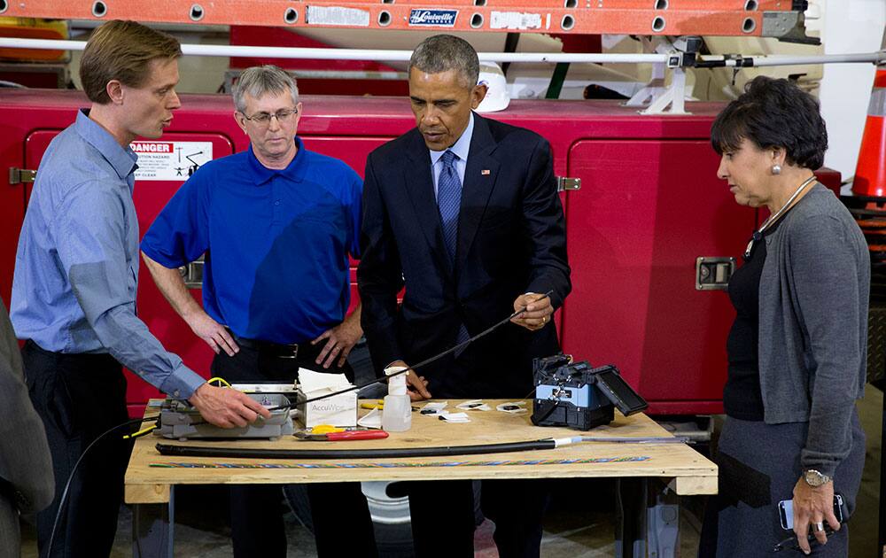 President Barack Obama, joined by Robert Houlihan, Chief Technology Officer at Cedar Falls Utilities, left, and David Schilling, Communications Services Manager at Cedar Falls Utilities, second from left and Commerce Secretary Penny Pritzker, attends a fiber optic splicing demonstration at Cedar Falls Utilities in Cedar Falls, Iowa.