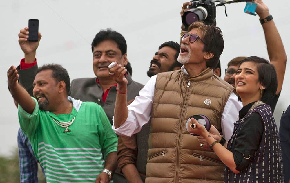 Bollywood actor Amitabh Bachchan, flies a kite as actors Dhanush and Akshra Hasan watch during the kite festival in Ahmadabad.