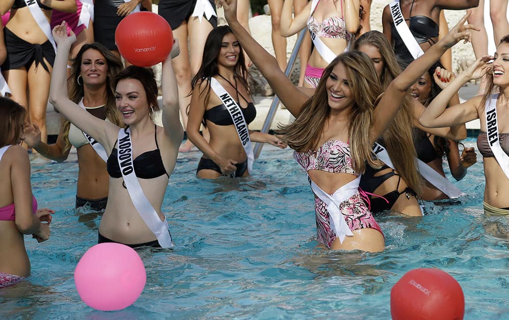 Miss Universe contestants Artnesa Krasniqi, of Kosovo, left, and Migbelis Castellanos, of Venezuela, right, pose in the water during the Yamamay swimsuit runway show.