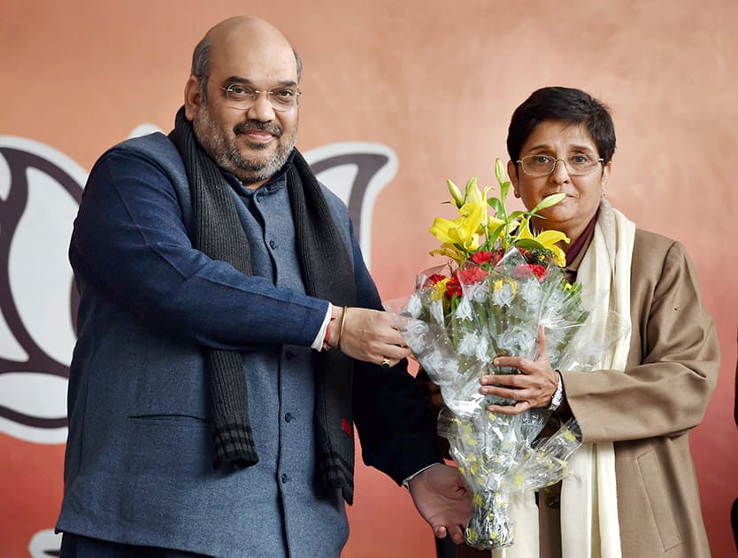 National BJP President Amit Shah presents a bouquet to former IPS officer Kiran Bedi to welcome her into the party during a press conference in New Delhi.