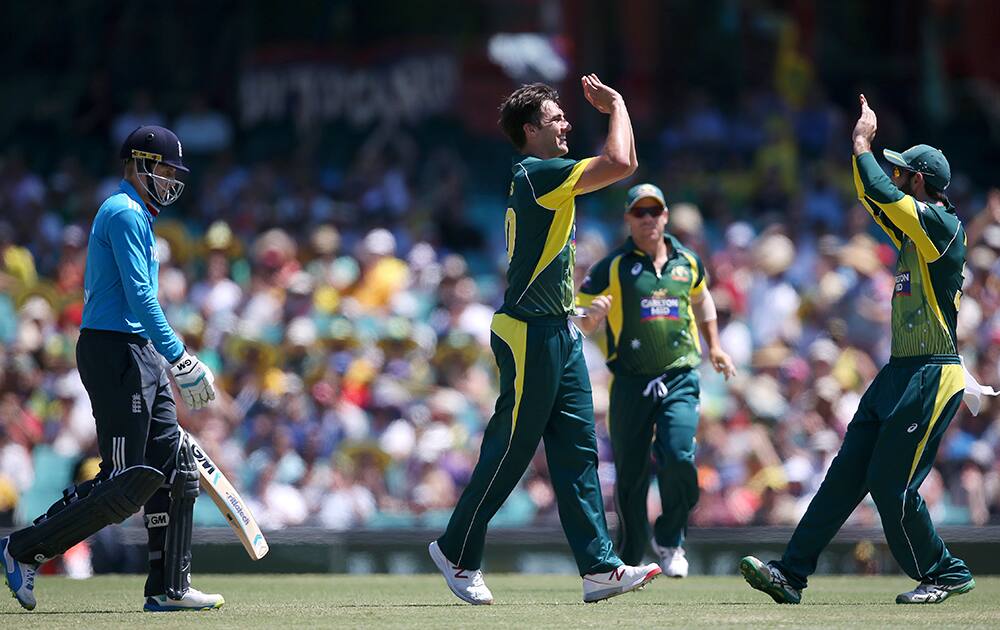 Australia's Pat Cummins, second right, celebrates with teammates after taking the wicket of England's Joe Root, left, caught for 5 runs during their one-day International cricket match in Sydney.