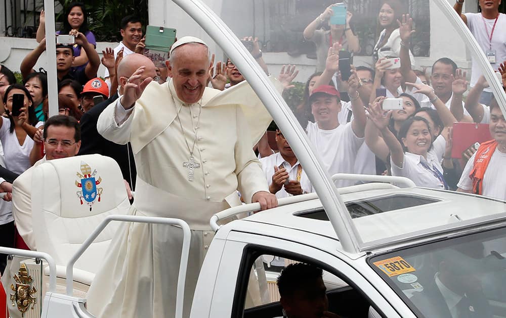 Pope Francis waves to the faithful from his Popemobile as his motorcade leaves the Presidential Palace for the Manila Cathedral, in Manila, Philippines.