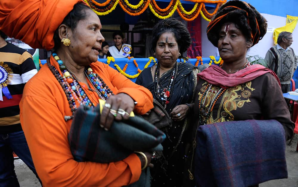 Hindu holy women talk after receiving blankets distributed by charitable trusts at a transit camp on the way to Gangasagar, in Kolkata.