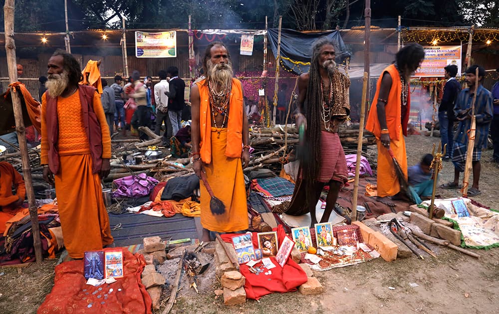 Sadhus, or Hindu holy men, look to attract pilgrims to receive offerings at a transit camp on the way to Gangasagar, in Kolkata.