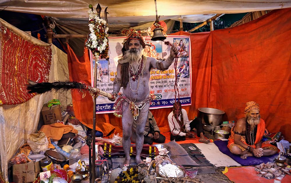 A Naga sadhu or naked Hindu holy man rings a bell to attract pilgrims to receive offerings at his resting place inside a transit camp on the way to Gangasagar, in Kolkata.