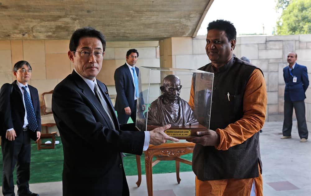 Japanese Foreign Minister Fumio Kishida, poses with a bust of Mahatma Gandhi presented to him during his visit to the Gandhi memorial in New Delhi.