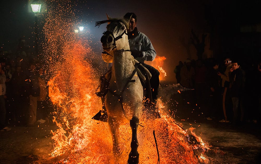 A man rides a horse through a bonfire as part of a ritual in honor of Saint Anthony the Abbot, the patron saint of domestic animals, in San Bartolome de Pinares, about 100 kilometers (62 miles) west of Madrid, Spain.