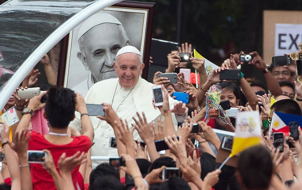 Pope Francis passes past a portrait of himself as he arrives to meet youths in Santo Tomas University in Manila, Philippines.