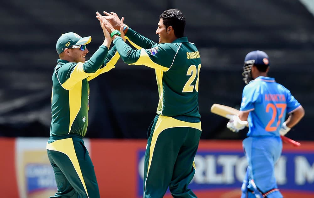 Australian players Aaron Finch and Gurinder Sandhu celebrate the wicket of India's Ajinkya Rahane, right, during their one-day international cricket match in Melbourne.