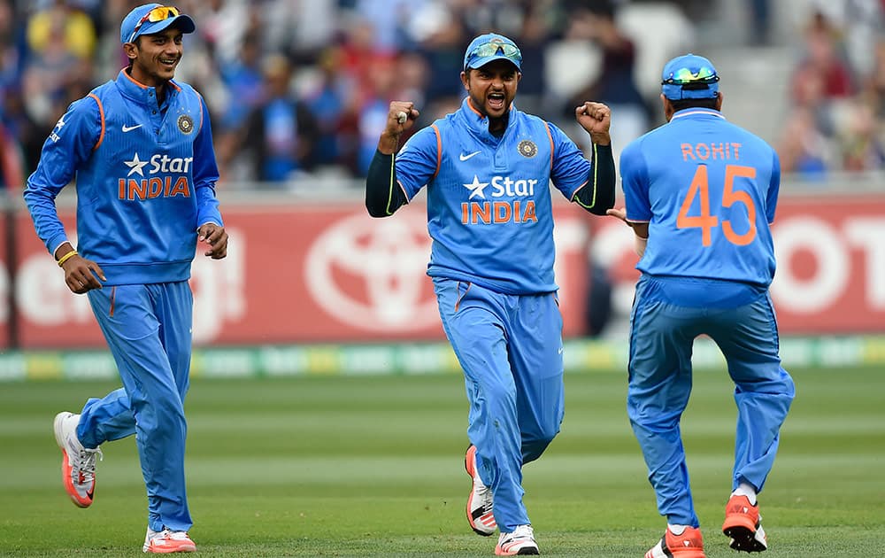 India's Suresh Raina, celebrates with teammates Akshar Patel, and Rohit Sharma, after catching out Australia's David Warner during their One Day International cricket match in Melbourne, Australia, Sunday.