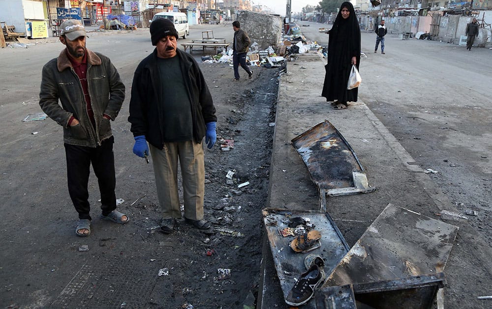 Iraqis inspect burned shoes that remain at the scene of a Saturday bomb explosion in Baghdad's Shiite district of Sadr City, Iraq, Sunday. A series of bombings targeting busy markets in and around the capital, Baghdad.