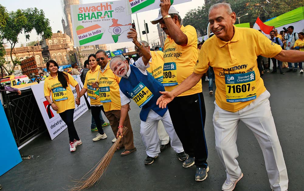 A participant, wearing a mask of India's Prime Minister Narendra Modi, holds a broom to join a countrywide campaign to clean parks, public building and streets, during the Mumbai Marathon in Mumbai.