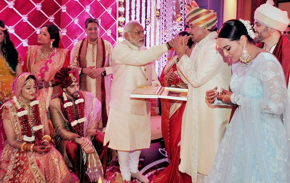 Prime Minister Narendra Modi gives a piece of sweet to Bharatiya Janata Party (BJP) MP Shatrughan Sinha on the occasion of his son, Kussh Sinhas wedding in Mumbai.