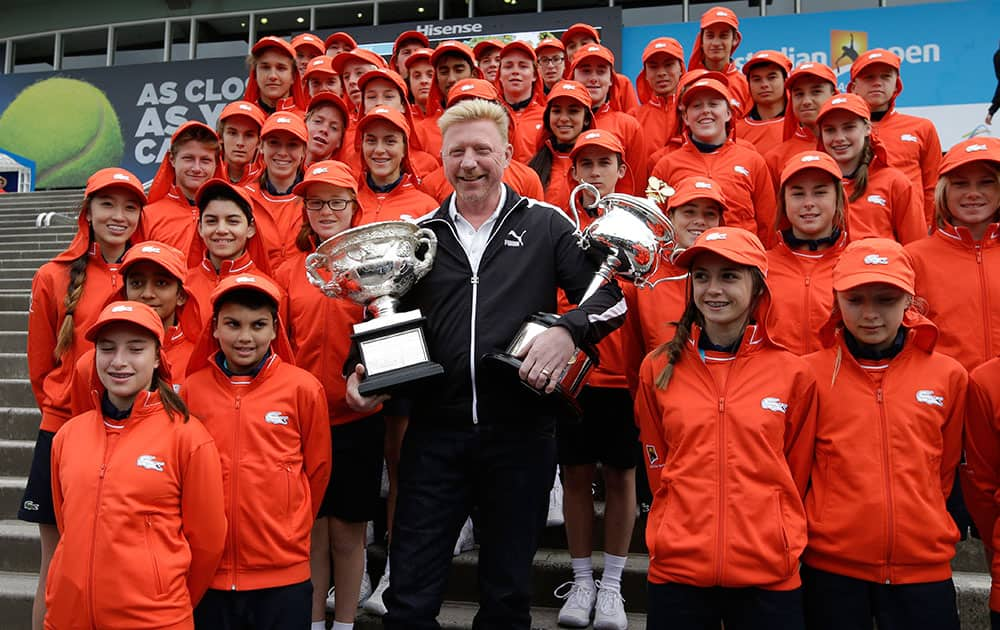 Former Australian Open champion Boris Becker holds the trophies of the men's singles and women's singles with ball kids, ahead of the first matches of this year's Australian Open tennis championship in Melbourne.