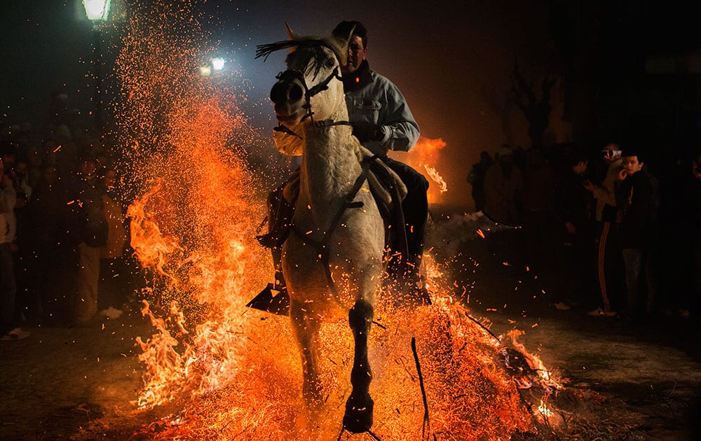 A man rides a horse through a bonfire as part of a ritual in honor of Saint Anthony the Abbot, the patron saint of domestic animals, in San Bartolome de Pinares, about 100 kilometers (62 miles) west of Madrid.