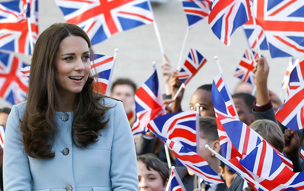 Britain's Kate, the Duchess of Cambridge walks past pupils with flags during a visit to formally open Kensington Aldridge Academy in London.