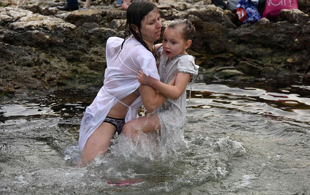 A woman and her daughter jump into water in Sevastopol, Crimea. Thousands of Russian Orthodox Church followers plunged into icy rivers and ponds across the country to mark Epiphany, cleansing themselves with water deemed holy for the day.