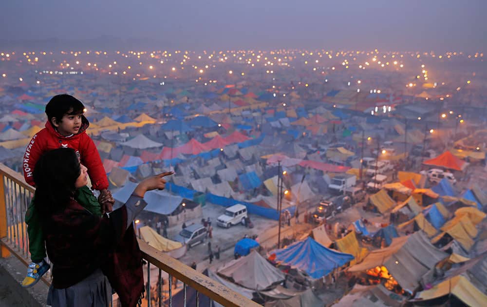 An Indian woman shows her child makeshift tents of Hindu devotees at the confluence of the rivers Ganges, Yamuna and the mythical Saraswati, on the eve of “Mauni Amavasya” or new moon day, considered the most auspicious date of bathing during the annual month long Hindu religious fair “Magh Mela” in Allahabad, India.