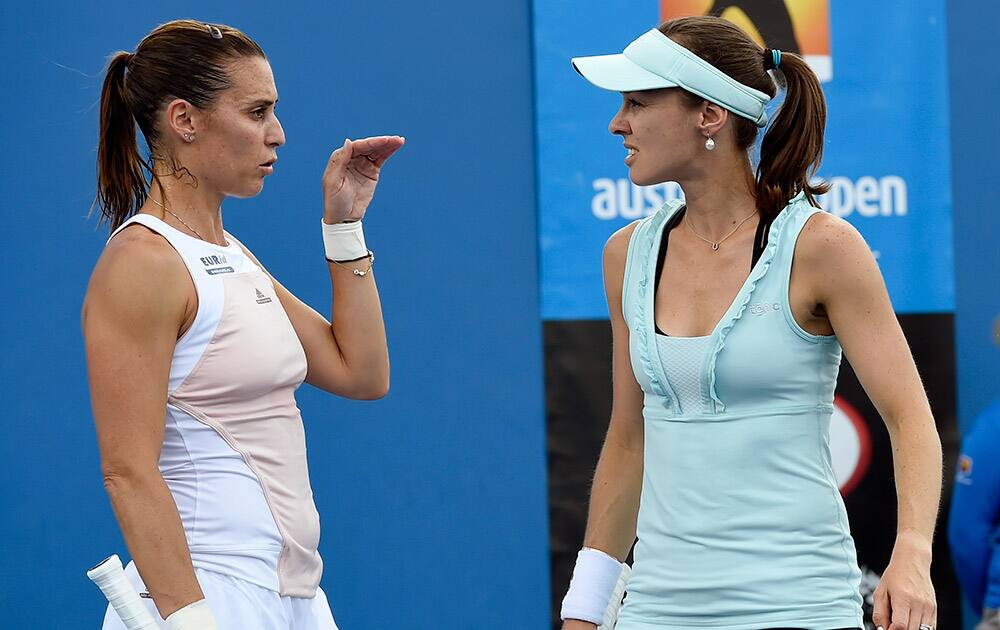 Martina Hingis of Switzerland, right, and playing partner Flavia Pennetta of Italy talk as they play Katerina Siniakova of the Czech Republic and Belinda Bencic of Switzerland during their first round women's doubles match at the Australian Open tennis championship in Melbourne.