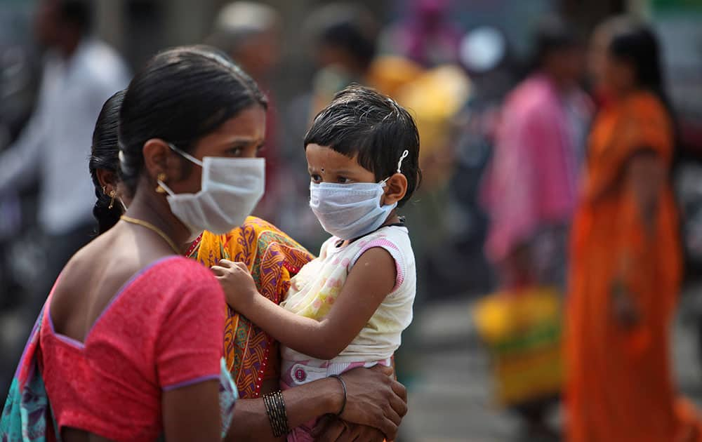 A woman and a child cover themselves with protective masks after the news of the outbreak of swine flu virus as they walk inside the premises of Gandhi Hospital in Hyderabad, India