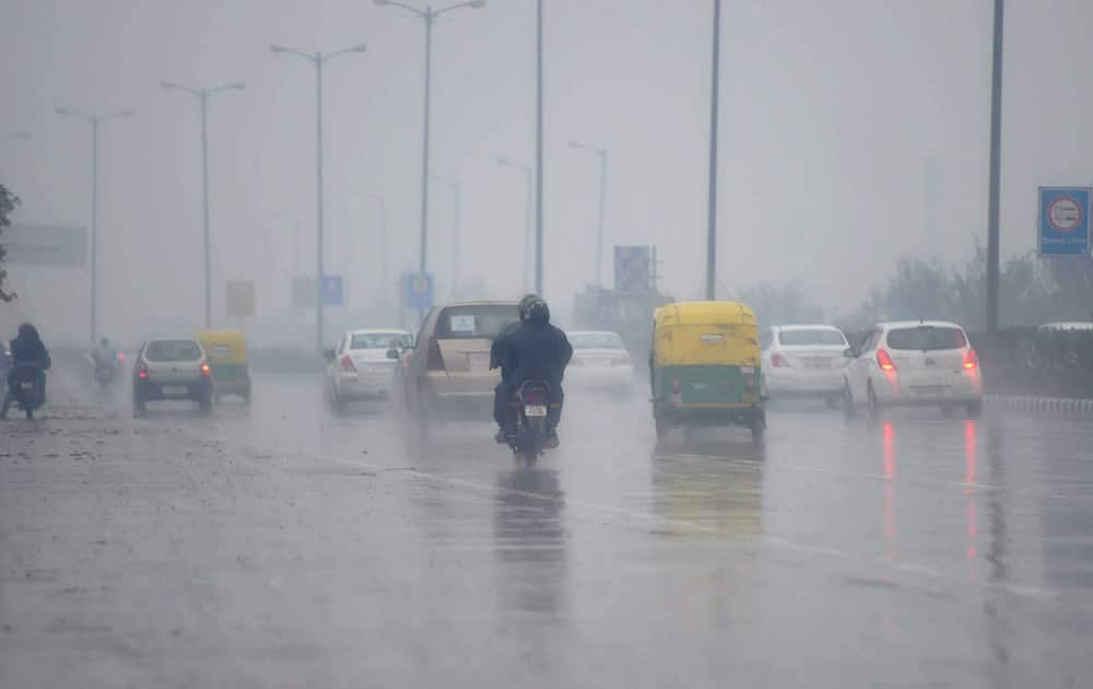 Vehicles plying at a road during rains in New Delhi.