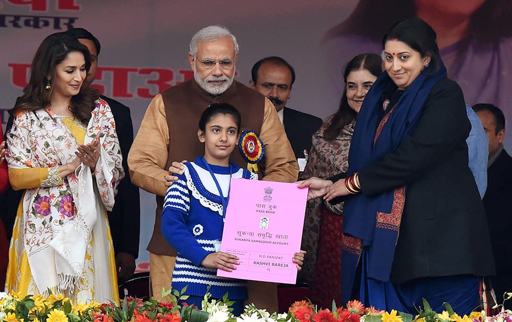 Prime Minister Narendra Modi with Union HRD Minister Smriti Irani presenting the Sukanya Samriddhi account pass-book to a girl during its launch at Beti Bachao Beti Padhao programme in Panipat.