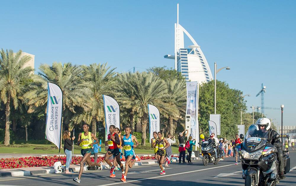 Elite runners in the Standard Chartered Dubai Marathon 2015 pass by the Burj al-Arab at around the 30 kilometer mark, in Dubai, UAE.