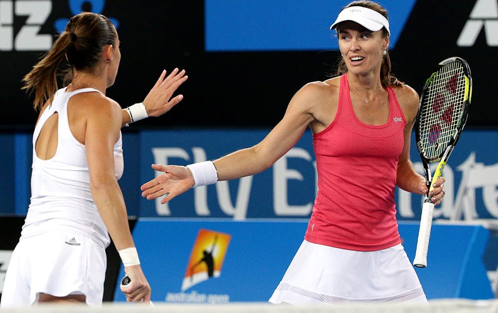 Martina Hingis of Switzerland and Flavia Pennetta of Italy touch hands as they play Daniela Hantuchova of Slovakia and Karin Knapp of Italy during their women's doubles second round match at the Australian Open tennis championship in Melbourne, Australia.