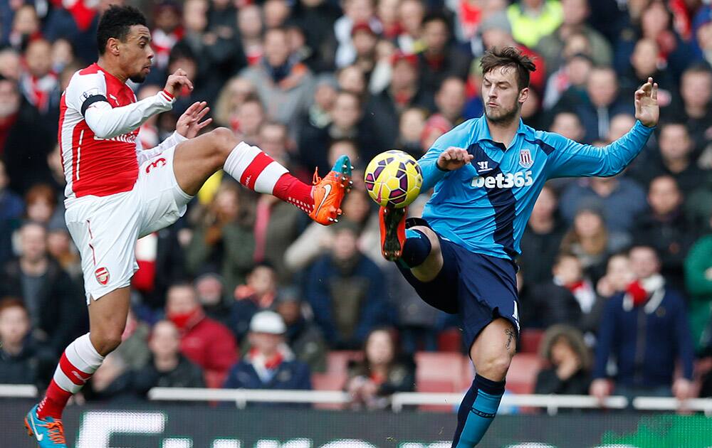 Arsenal's Francis Coquelin, left, challenges Stoke City's Marko Arnautovic for the ball during their English Premier League soccer match between Arsenal and Stoke City at the Emirates stadium in London.