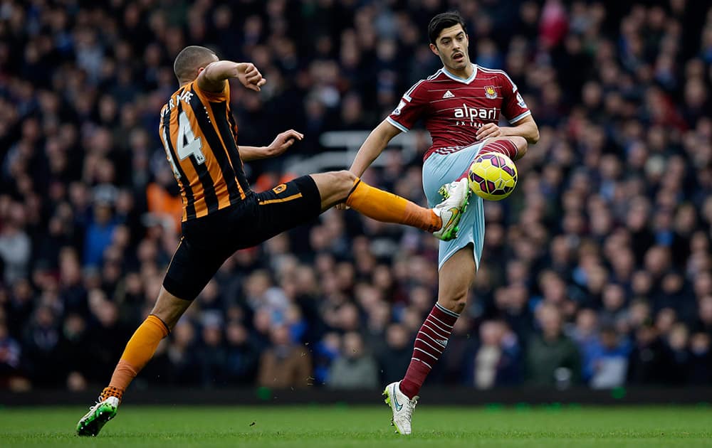 West Ham's James Tomkins, right, competes for the ball with Hull City's Jake Livermore during the English Premier League soccer match between West Ham and Hull City at Upton Park stadium in London.