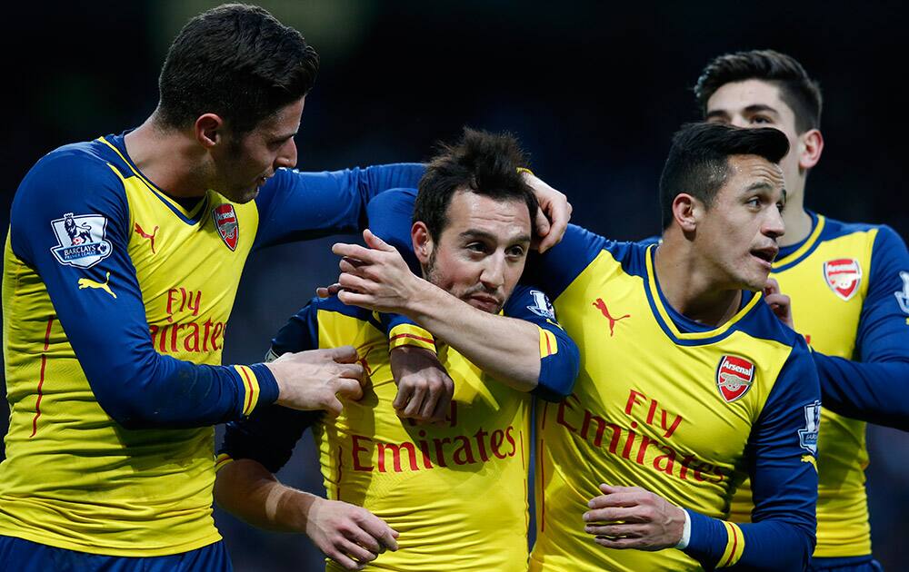 Arsenal's Santi Cazorla, second left, celebrates with teammates after scoring the opening goal of the game from the penalty spot during the English Premier League soccer match between Manchester City and Arsenal at the Etihad Stadium, Manchester, England.