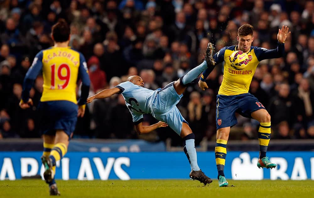 Manchester City's Fernandinho, centre, challenges Arsenal's Olivier Giroud, right, for the ball during the English Premier League soccer match between Manchester City and Arsenal at the Etihad Stadium, Manchester.