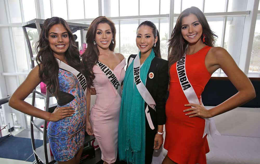 Miss Universe contestants Noyonita Lodh, left, of India, Mary Jean Lastimosa, second from left, of the Philippines, Keiko Tsuji, second from right, of Japan, and Paulina Vega of Colombia pose for photos during a break in rehearsals, Saturday, Jan. 24, 2015, At Florida International University in Miami. 