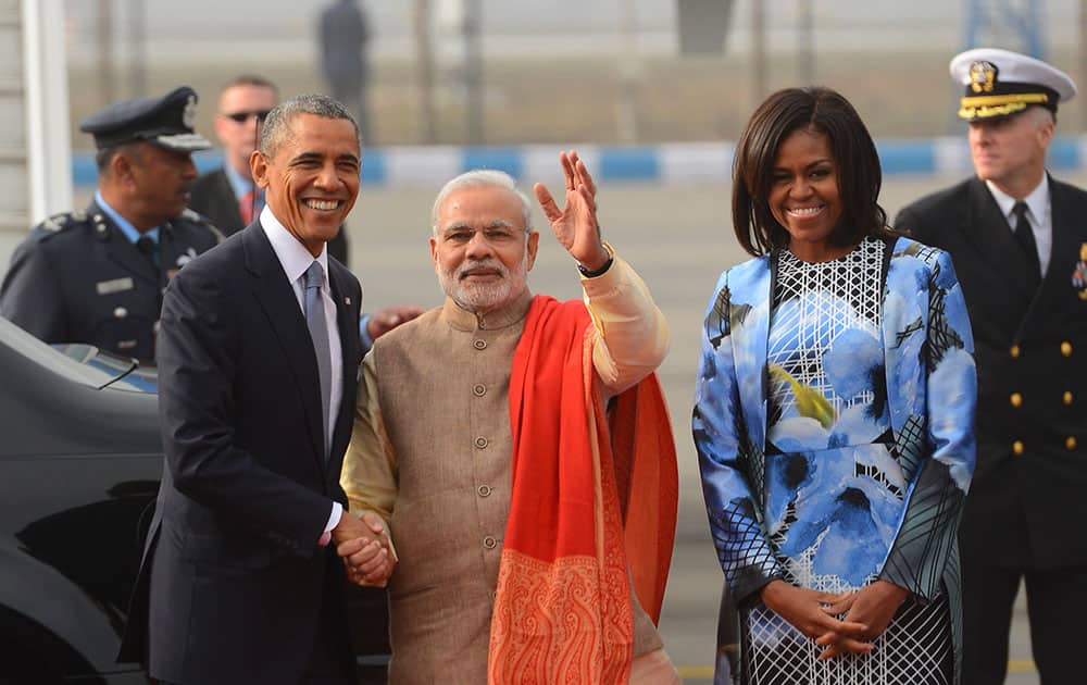 US President Barack Obama shakes hand with Indian Prime Minister Narendra Modi as first lady Michelle Obama stands beside them, upon arrival at the Palam Air Force Station in New Delhi, India