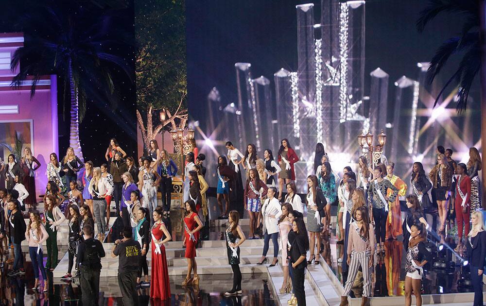 Miss Universe contestants stand in place during a break in rehearsals, at Florida International University in Miami.