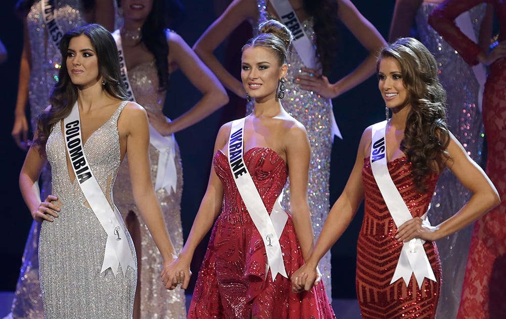 Paulina Vega of Colombia, left, Diana Harkusha of Ukraine, center, and Nia Sanchez of the U.S., hold hands as the wait for the announcement of the second runner up during the Miss Universe pageant in Miami.