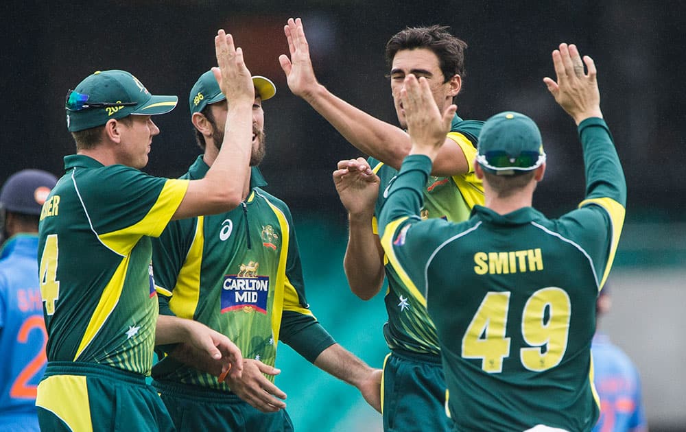 Australian Mitchell Starc, no cap, is congratulated by teammates Steve Smith, right, James Faulkner and Glen Maxwell after Starc claimed the wicket of Indian Shikhar Dhawan during their one-day international cricket match in Sydney.