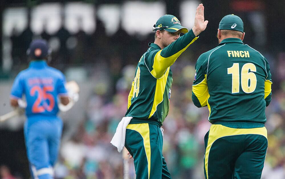 Australian Steve Smith, high fives teammate Aaron Finch after catching Indian Shikhar Dhawan during their one-day international cricket match in Sydney.