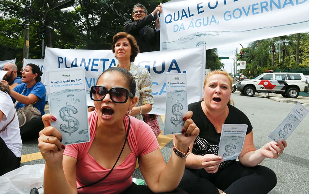 Demonstrators hold signs that reads in Portuguese 