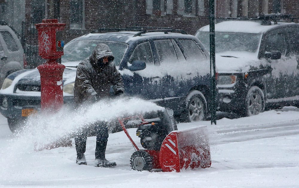 A man uses a snowblower to clear a path in the Windsor Terrace neighborhood, in the Brooklyn borough of New York.