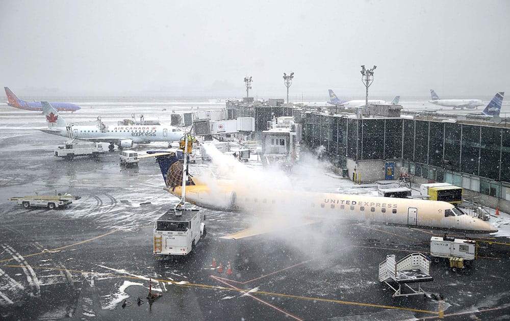 A plane is de-iced at LaGuardia Airport in New York. Airlines canceled thousands of flights into and out of East Coast airports as a major snowstorm packing up to 3 feet of snow barrels down on the region.