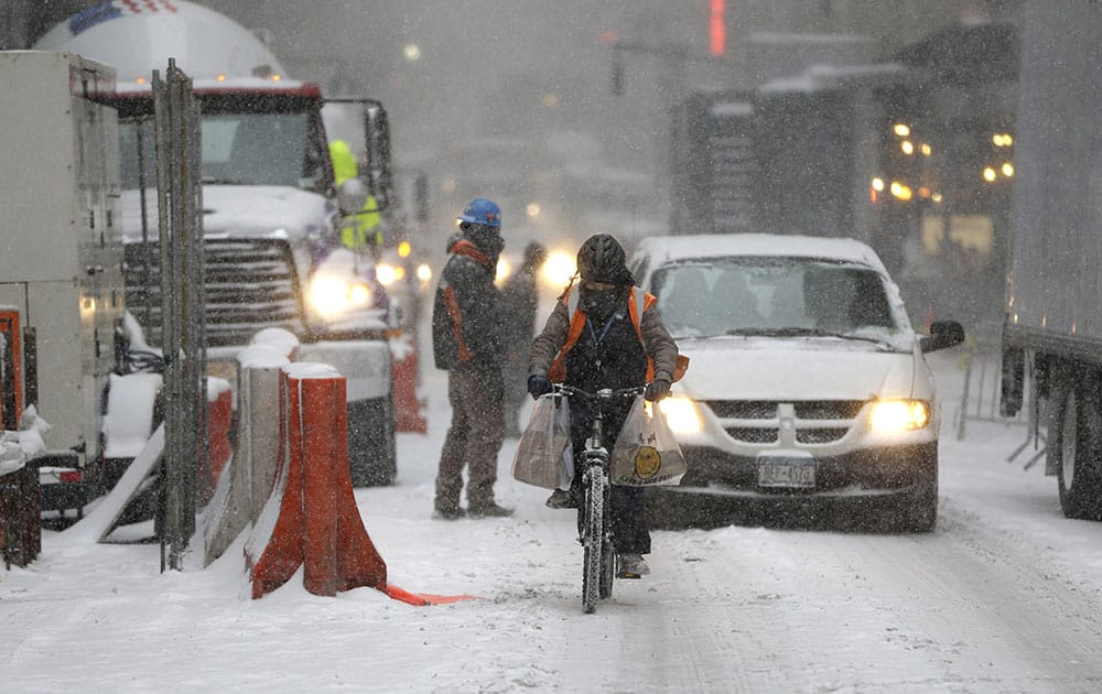 People make their way by bike or car through the streets of the midtown Manhattan in New York.