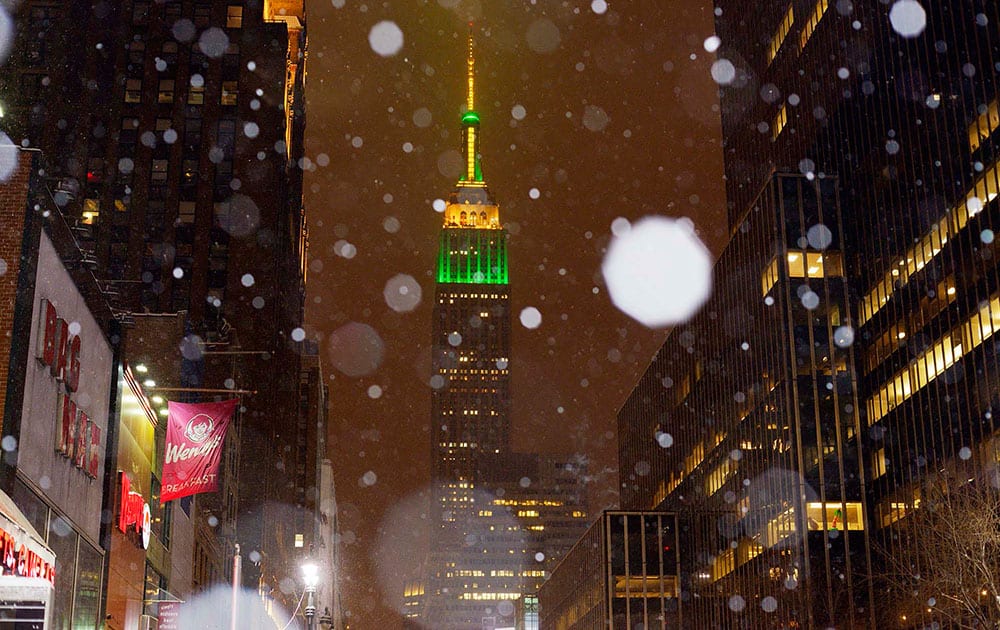 Snow falls around the Empire State Building in midtown Manhattan.