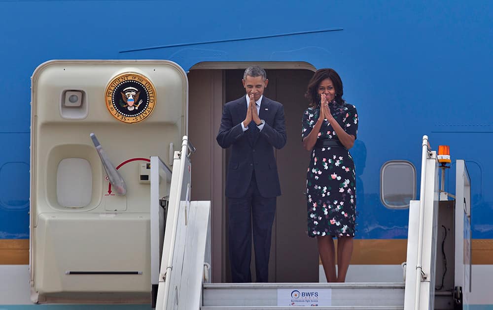 US President Barack Obama and first lady Michelle Obama fold their hands together in a traditional Indian greeting gesture as they prepare to board Air Force One in New Delhi.