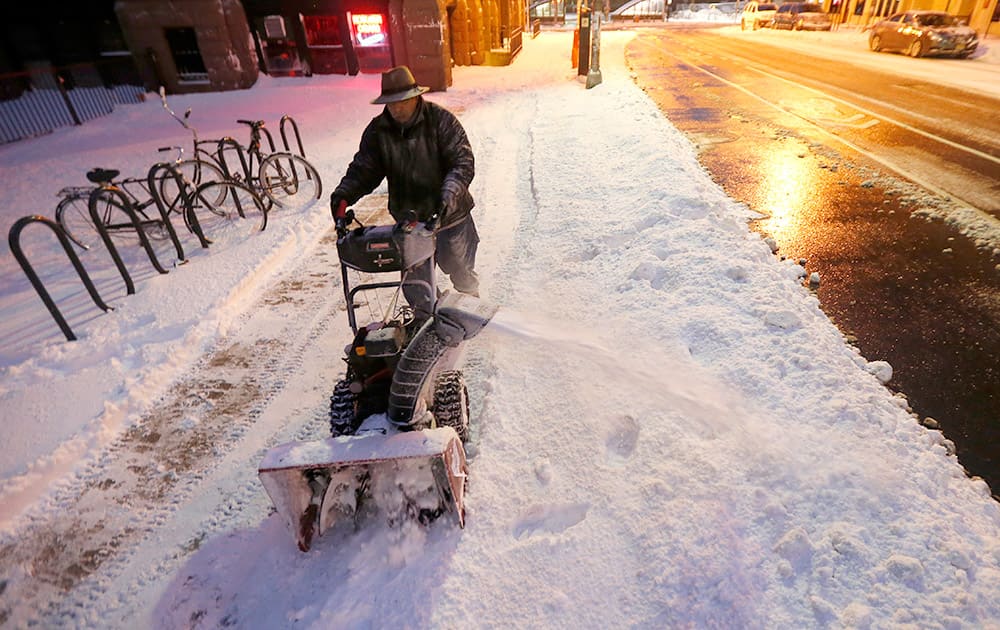 Roberto Perez uses a snowblower to clear a sidewalk following an overnight snowstorm, in Hoboken.